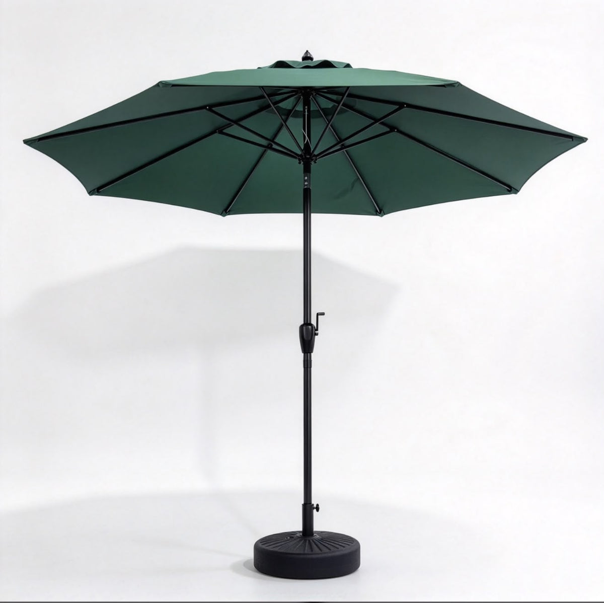 A dark green patio umbrella with a black pole, weighted round base, and top finial, shown open against a plain white studio background.